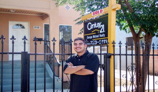 A smiling man standing outside of a recently sold home